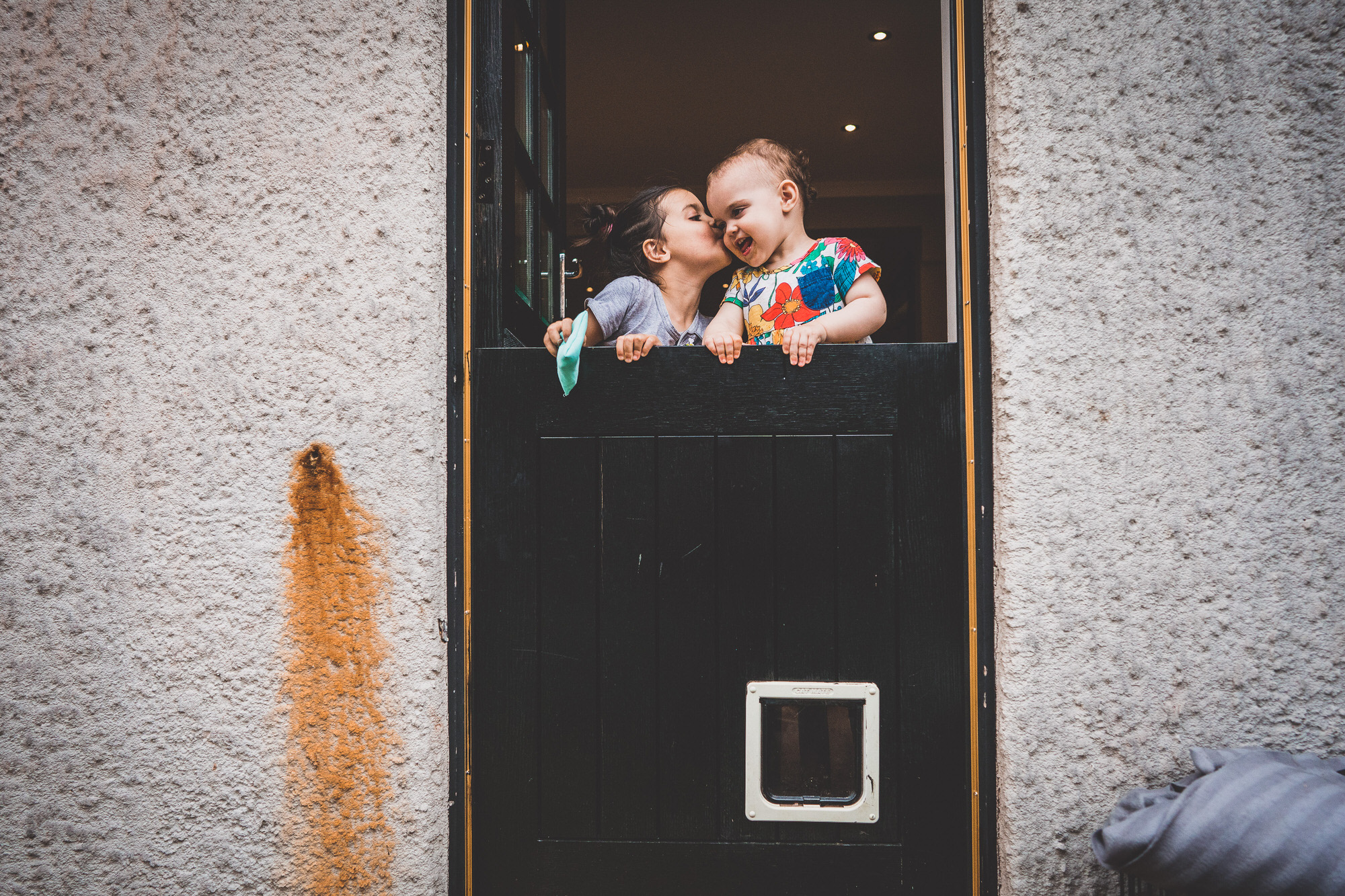 Wedding photographer captures a heartwarming moment of two children kissing joyfully on the big day.