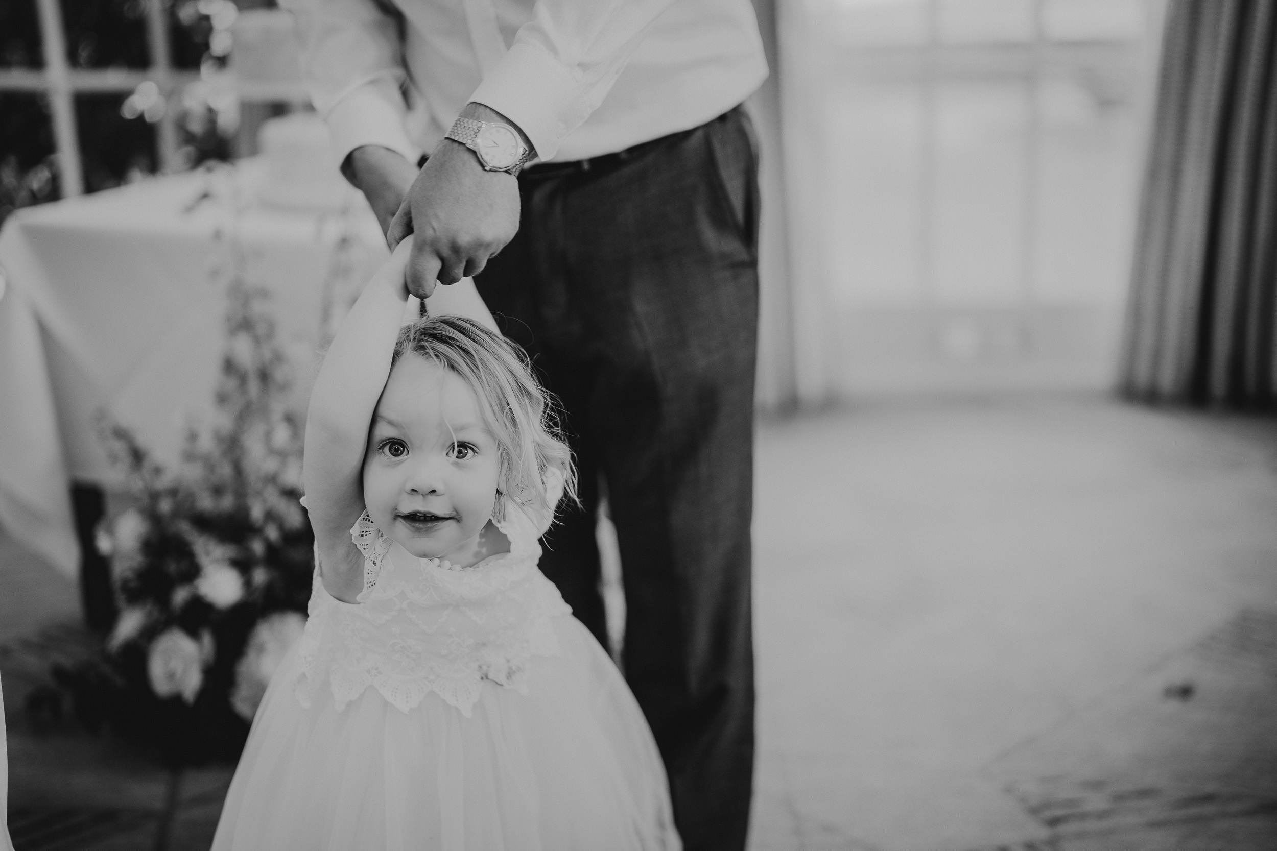 A child in a dress holds an adult's hand in a bright room.