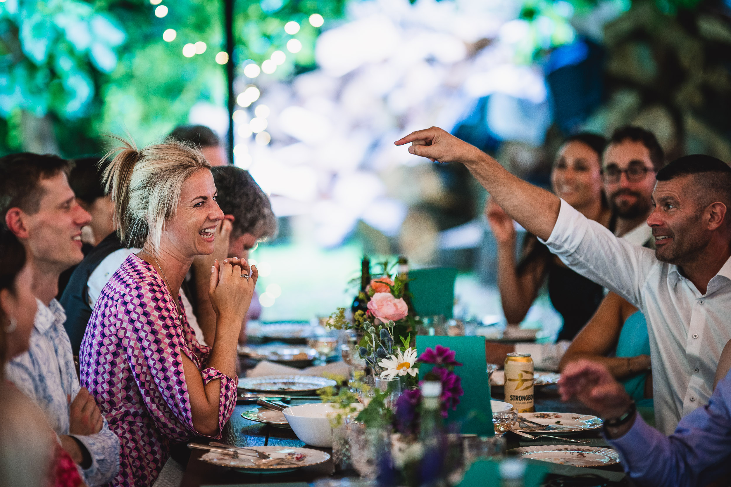 People enjoying a lively conversation at a decorated outdoor dining table, adorned with flowers and colorful tableware.