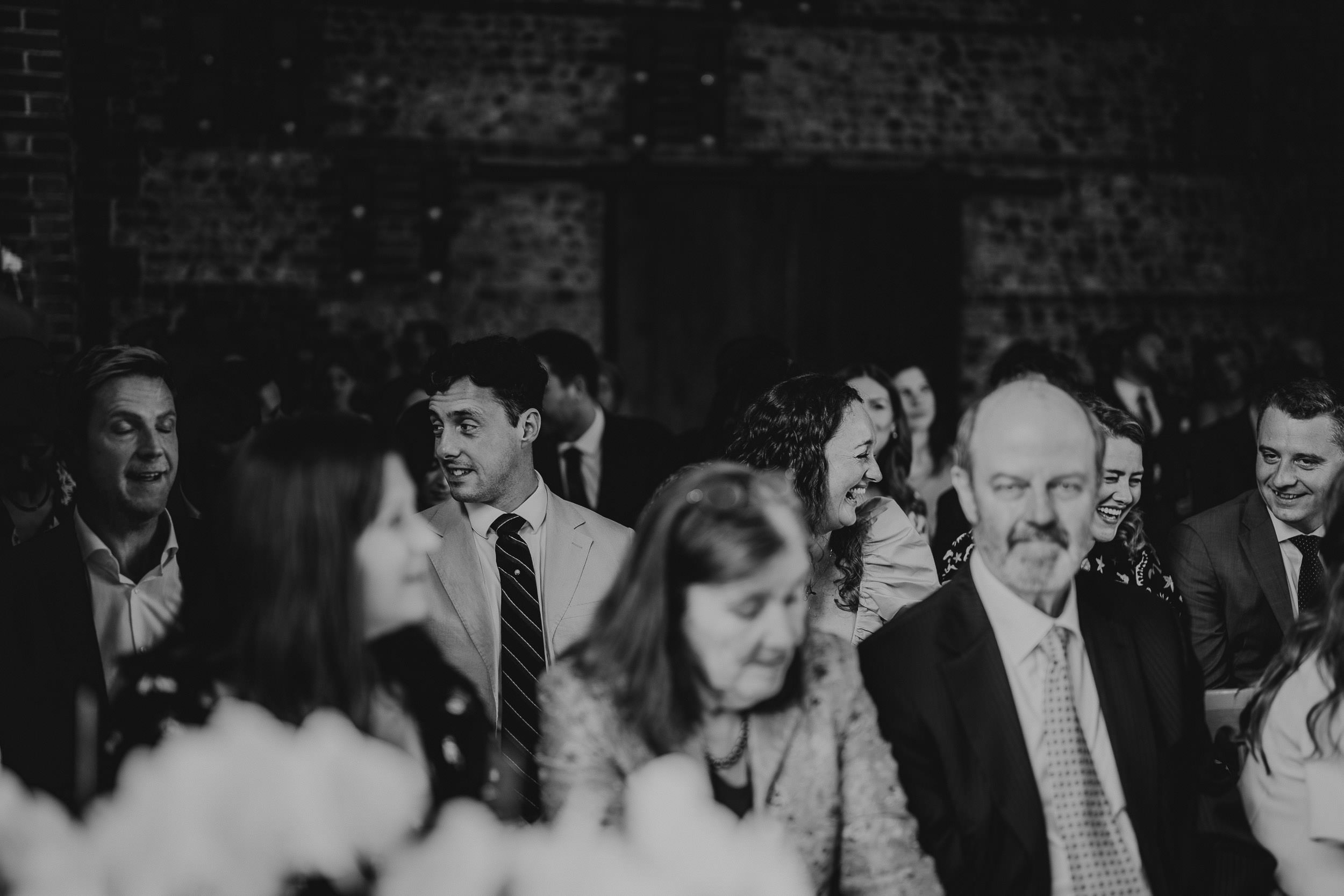 A black and white photo of a group of people sitting together indoors, engaged in conversation and facing forward.